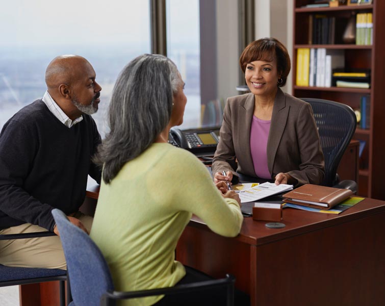 An older couple seated at the desk of a financial advisor.