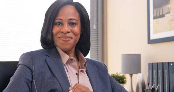 A smiling business woman seated behind a desk.