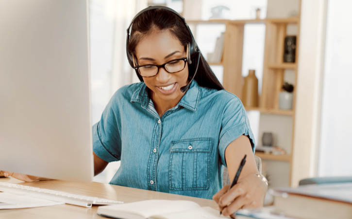 young businesswoman wearing headsets and working on a computer at home