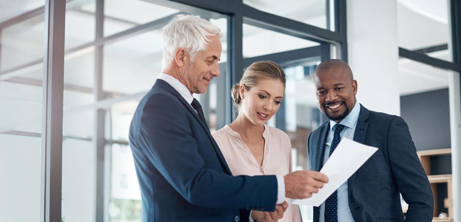 Des gens d’affaires discutant paperasse dans un bureau d’allure moderne.