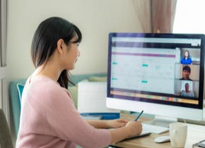 Une femme devant un écran d’ordinateur rédige une note.