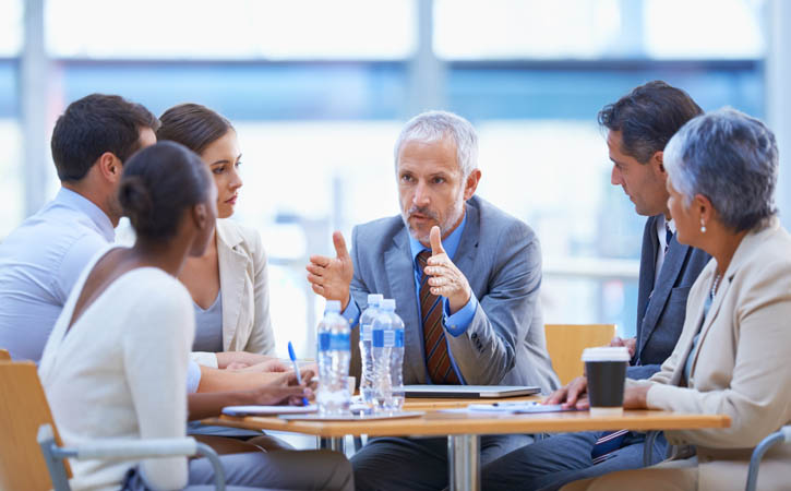 Un homme parle à un petit groupe de professionnels.