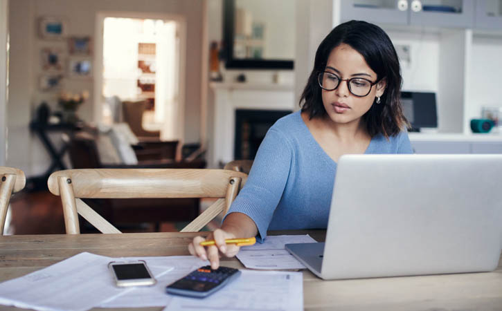 Une femme travaille de chez elle, sur la table de la salle à manger.
